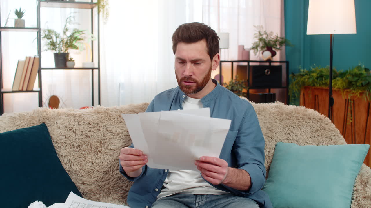 Young man frustrated and disappointed crumples a paper and throws it away while reviewing documents