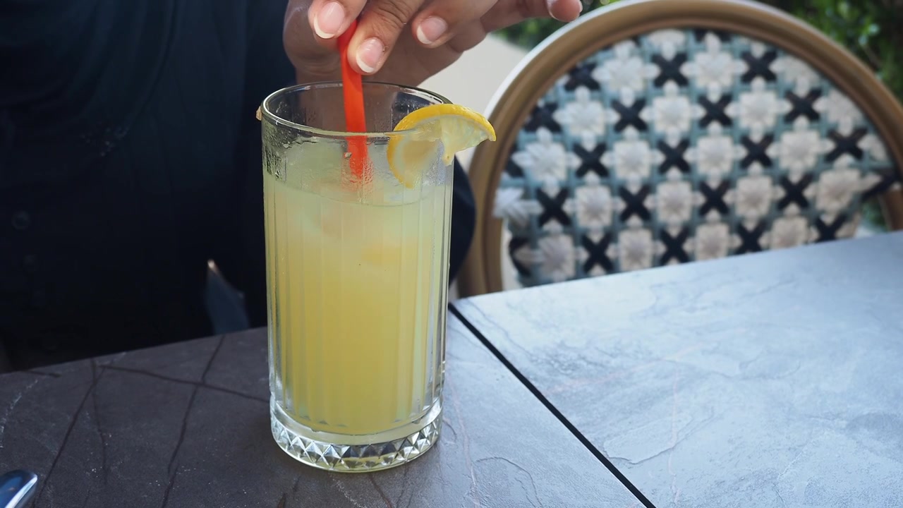 Persona che mescola un bicchiere di limonata fresca in un caffè all'aperto