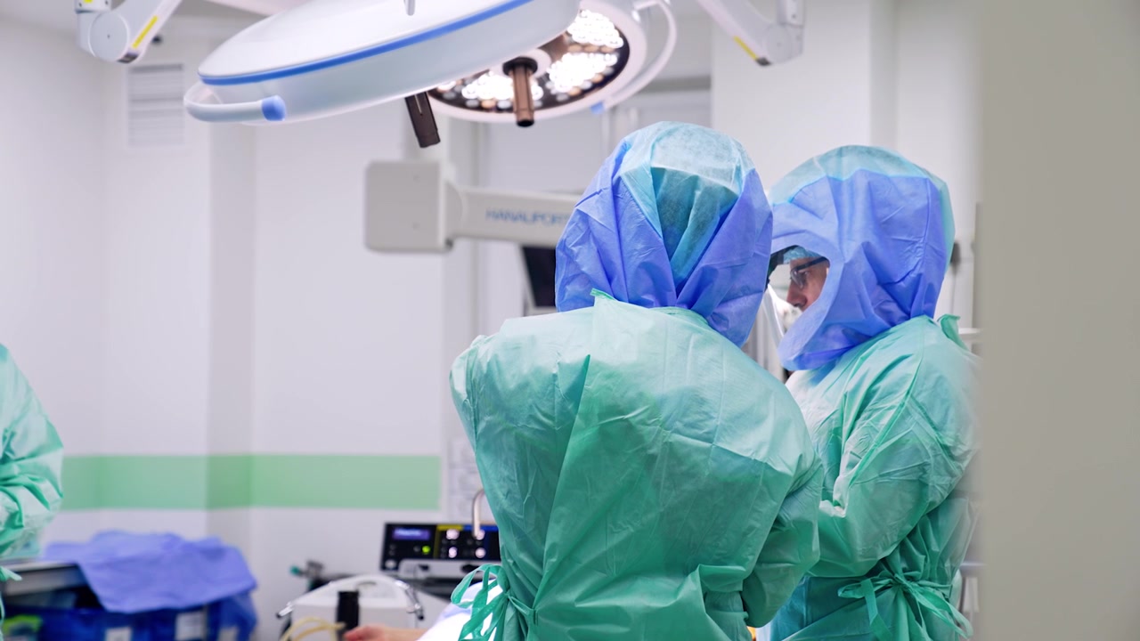 Distant view on the doctors wearing robes and protective helmets. Professional surgeons are getting ready for surgery in modern hospital.
