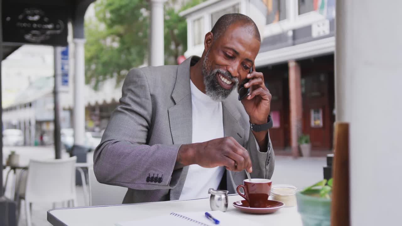 African American man talking by phone in a coffee