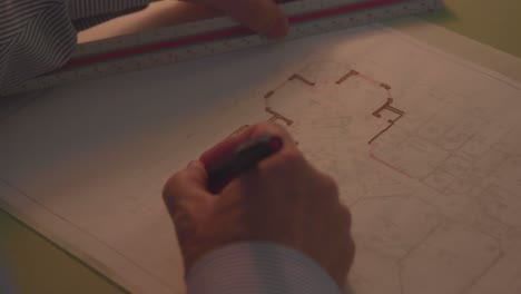 primer plano de un hombre dibujando un plano de casa dentro de una oficina de arquitectura