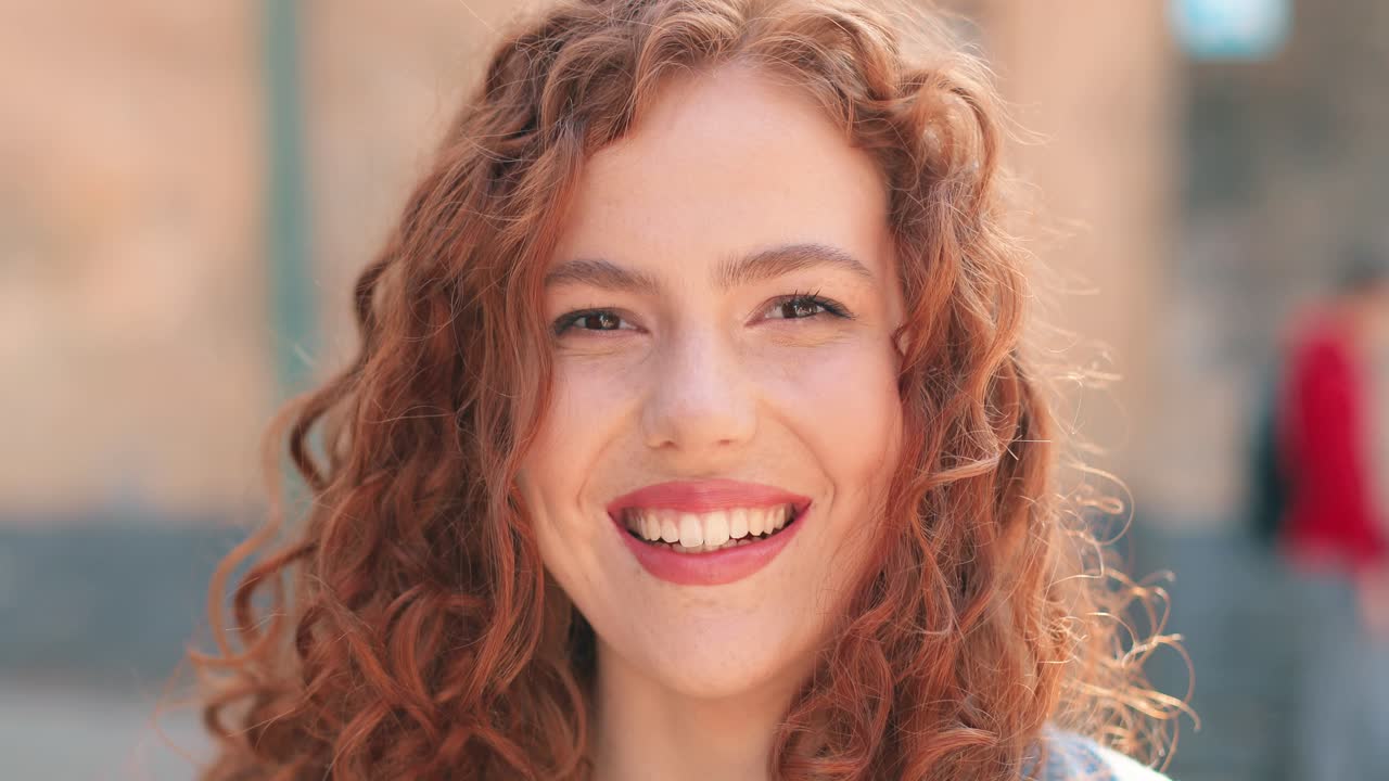 vista de cerca de una mujer pelirroja mirando a la cámara y sonriendo en la calle