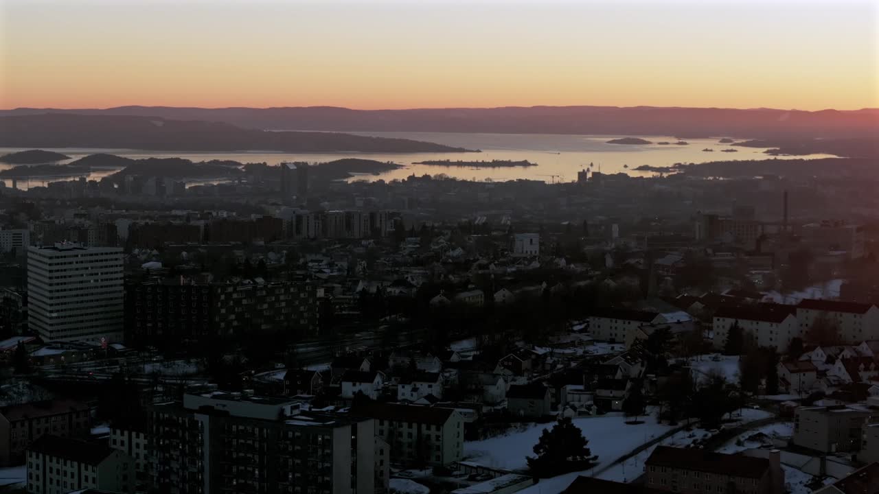 Norwegian arctic golden hour sunset Oslofjord Olso city downtown Norway Norge aerial drone inner coastline Hovedøya Lindøya islands apartment buildings highway cars cityscape forward motion