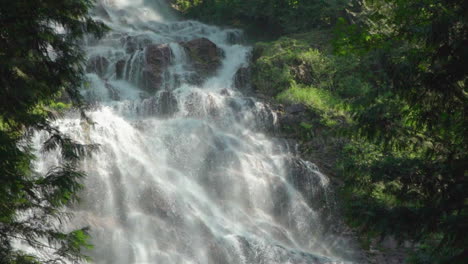 crepuscular rays coming off of a huge waterfall in the middle of the forest in slow motion