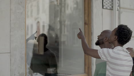 Happy-black-male-couple-window-shopping-and-hugging.