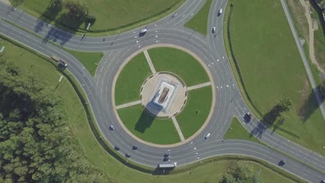 the drone camera rotates around a circular traffic ring on a city avenue.
