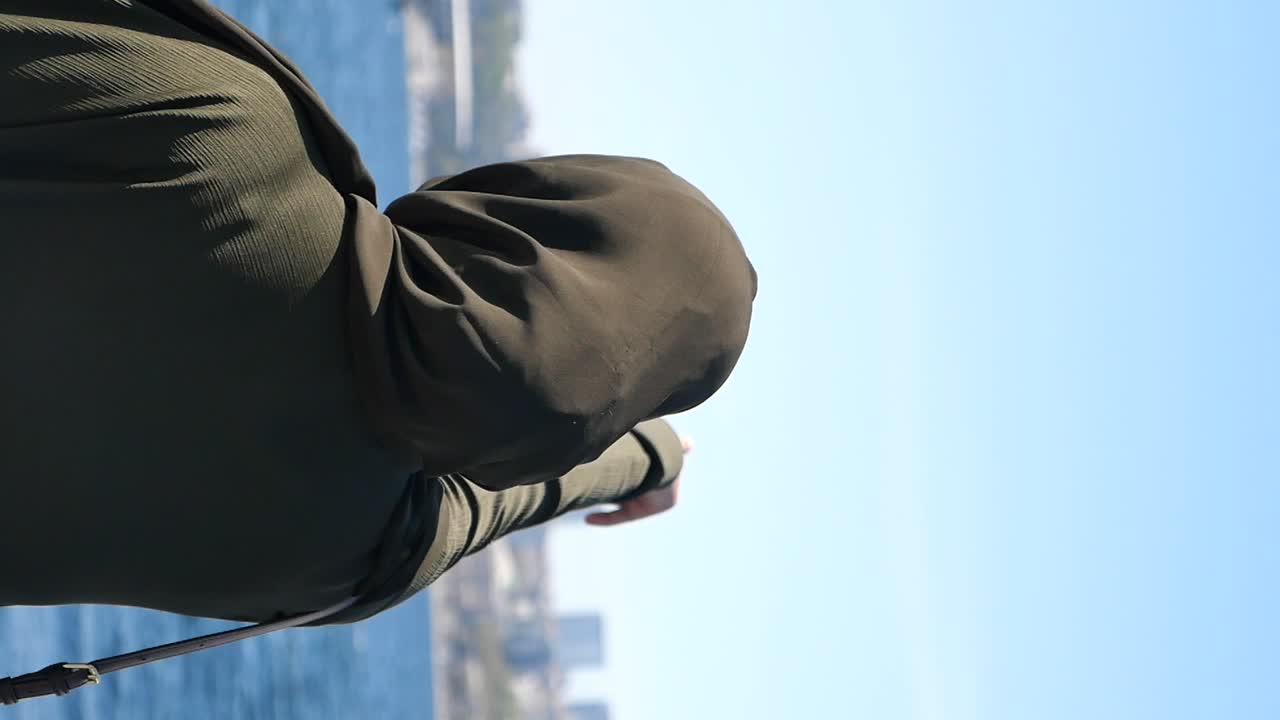 Woman in a Hoodie and Hijab Looking Out at the Sea