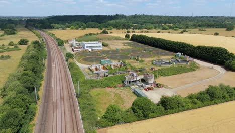 drone aerial view of wastewater treatment facility with sedimentation ponds and cake pads alongside railway england
