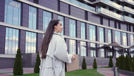 a happy woman is walking in front of an office building