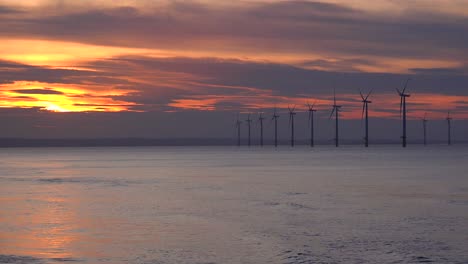 a wind farm generates electricity along a coastline at sunset