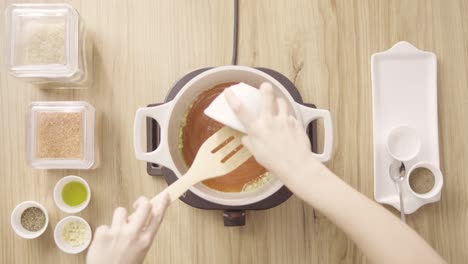 pouring red sauce, mixing it with garlic and stir, top view static