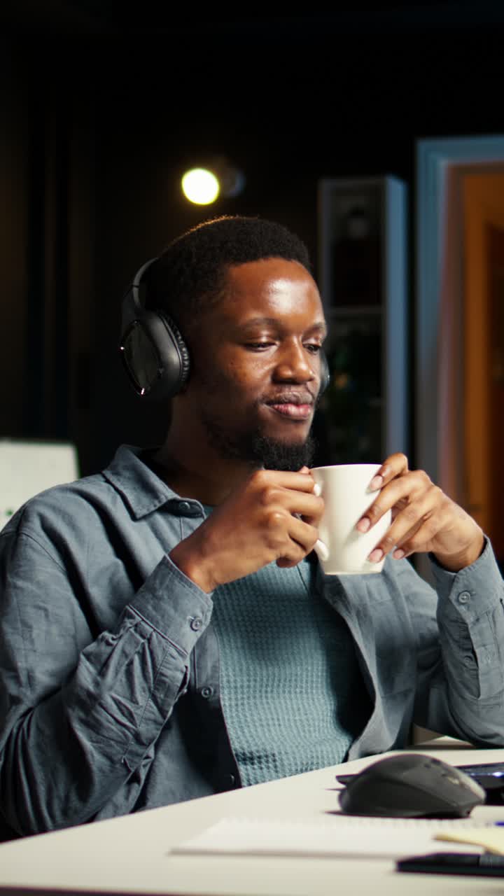 Homem trabalhando no computador com fones de ouvido e café