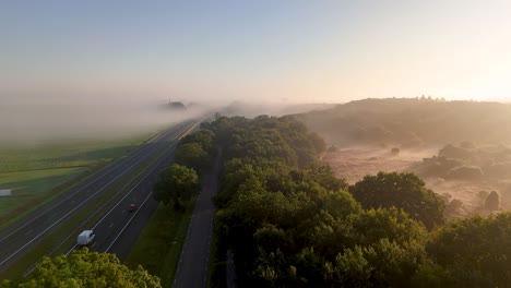 Aerial View of a Foggy Highway and Forest at Sunrise