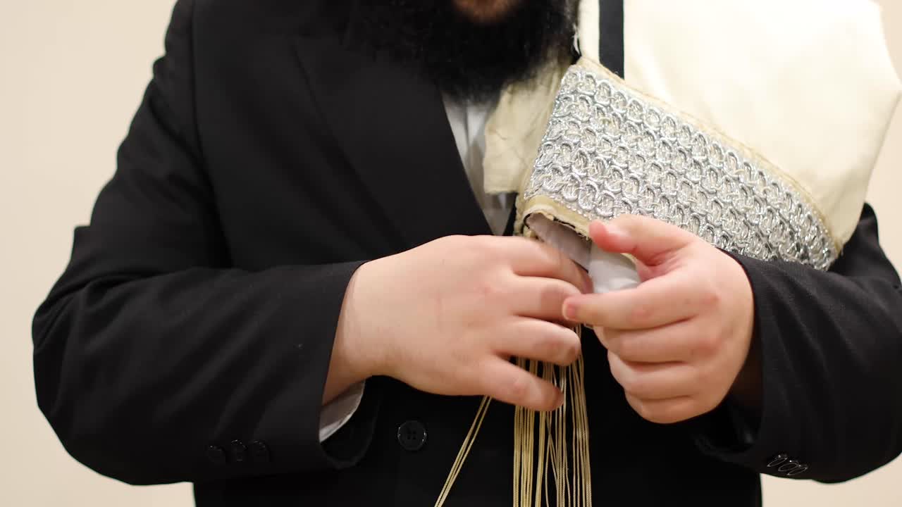 Jewish man checking tzitzit before prayer