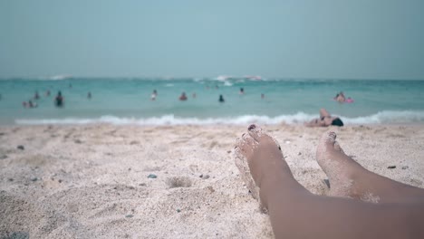 Mujer-Con-Pedicura-Roja-Toma-El-Sol-Tumbada-En-La-Arena-Cálida.