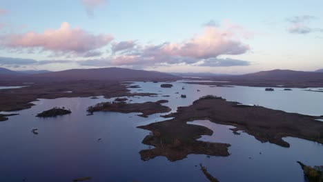 Eine-Drohne-Senkt-Sich-Langsam-Zu-Einer-Patchwork-Landschaft-Aus-Inseln-Zwischen-Süßwasserseen-Und-Torfmooren-Bei-Sonnenuntergang