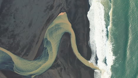 yellow river mouth on black sand beach in south iceland aerial footage