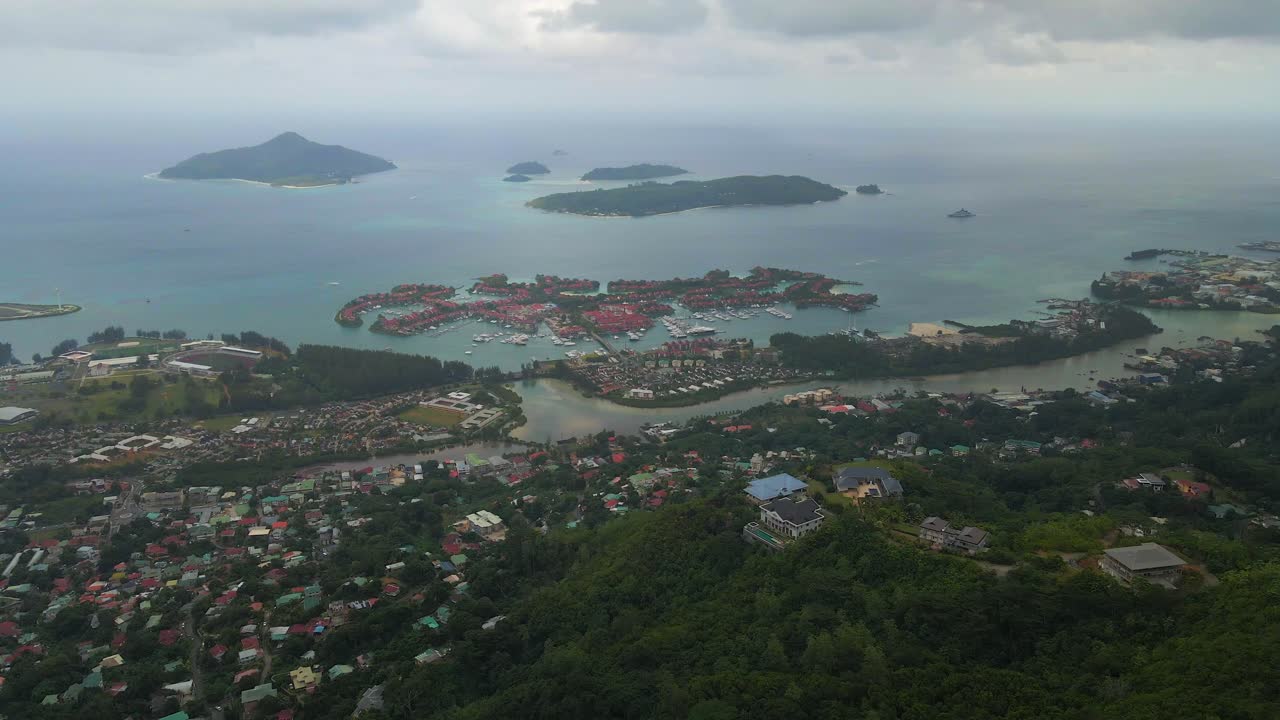 세이 ⁇ 의 풍경은 위에서 드론으로 촬영되어 주요 섬 마헤의 자연, 산, 집 및 섬을 보여줍니다.