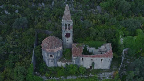 old cathedral ruins in lush green vegetation at kotor bay montenegro, aerial