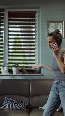 mujer discutiendo por teléfono en la sala de estar