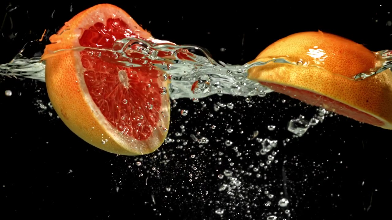 Zeitlupe: Rote Grapefruithälften spritzen ins Wasser