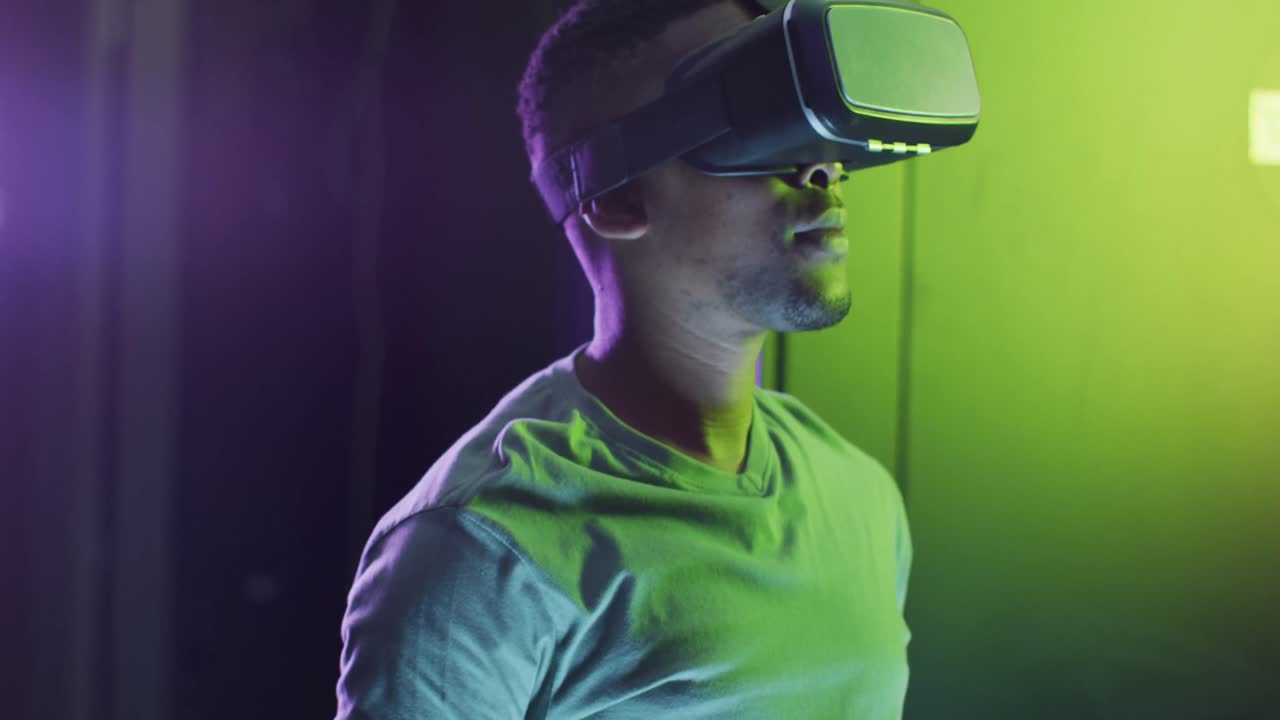 tecnico informatico maschio afroamericano che usa le cuffie vr che lavora in una sala server aziendale