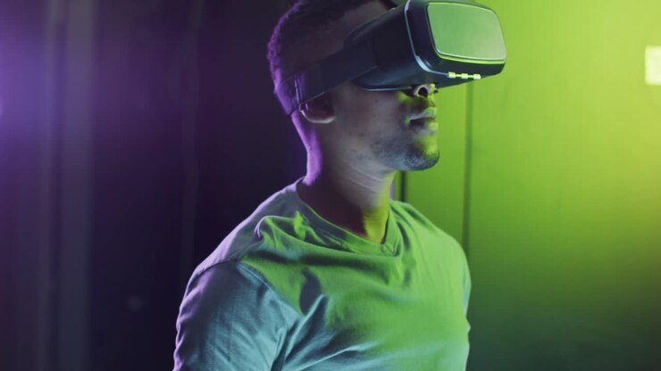 Tecnico informatico uomo afroamericano che usa un visore VR e lavora in una sala server aziendale