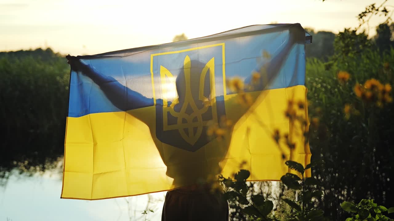 Symbol of hope and peace as woman raises Ukraine flag in golden hour light