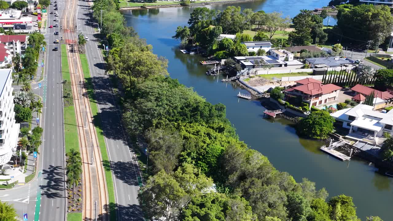 Toma de dron desde las alturas que capta el tráfico en la autopista junto al río Nerang y edificios de apartamentos residenciales.