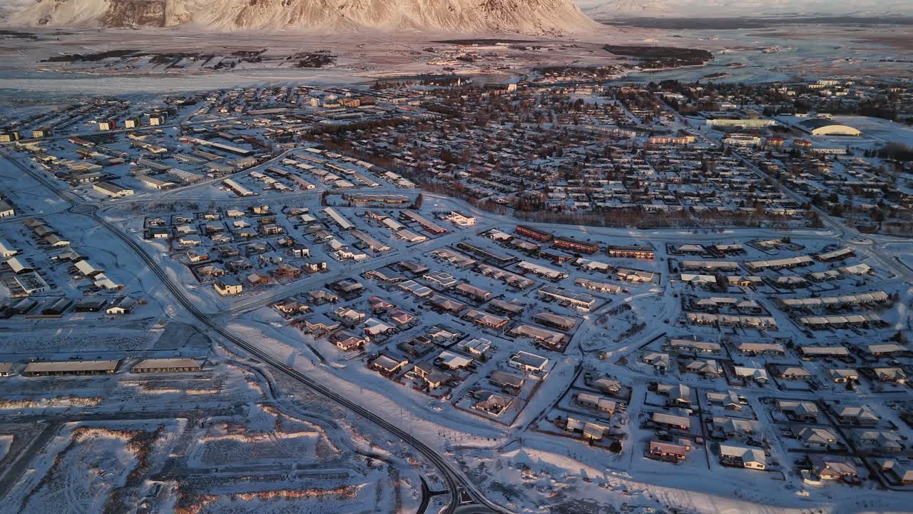Aerial shot of a town housing grid in Selfoss Iceland, panning up to reveal the mighty Ingólfsfjall mountain in the distance landscape