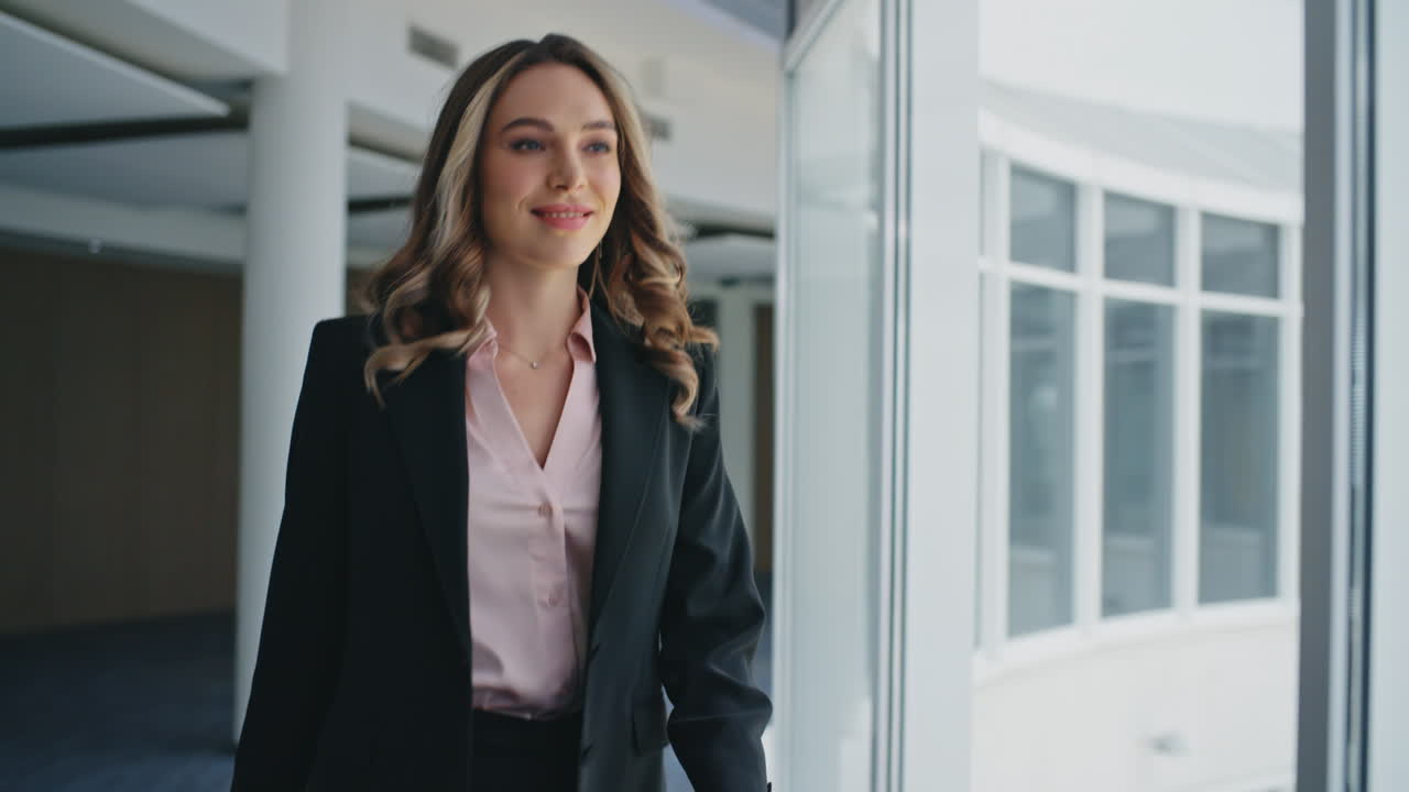 Empresaria feliz yendo al pasillo de la oficina. Primer plano de mujer exitosa caminando en traje.