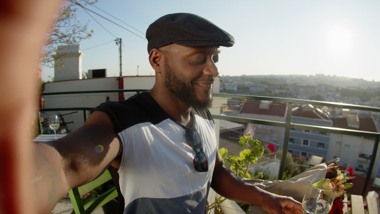 pov de gay afroamericano tomando selfie con ramo de flores y copa de vino