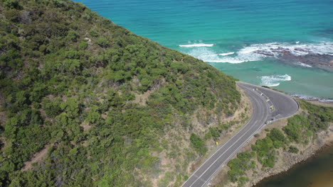 Hikers-walk-trail-high-above-coastal-beach-road-in-Victoria,-Australia