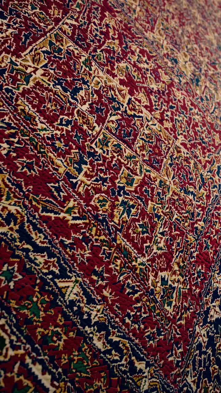 Persian carpet featuring elaborate geometric patterns, displaying rich textures and deep jewel-toned colors representing traditional Middle Eastern craftsmanship