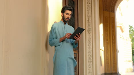 handsome indian man in light blue using a tablet