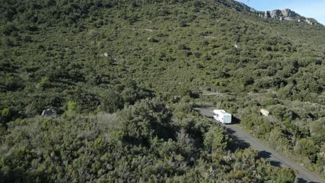 Camping-Car,-Caravan-Van-Drives-Up-the-Green-Mountain-Hills-Landscape-in-South-of-France,-Daylight-Summer,-Aerial-Drone-Shot