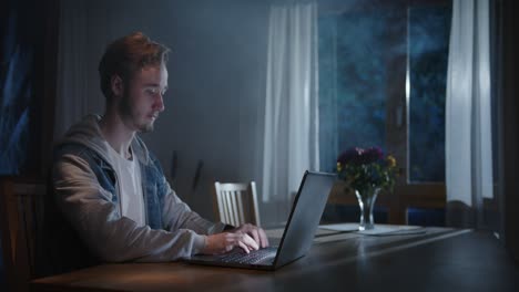 Alguien-Está-Escribiendo-En-La-Computadora-Portátil-En-La-Sala-De-Estar-Por-La-Noche-Con-Niebla-Y-Luz-Del-Exterior