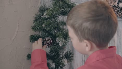 blond-son-watches-pine-cone-on-christmas-themed-decoration