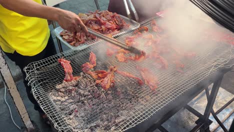 Street-food-vendor-cooking-bacon-on-charcoal-grill-at-night-market-Asia