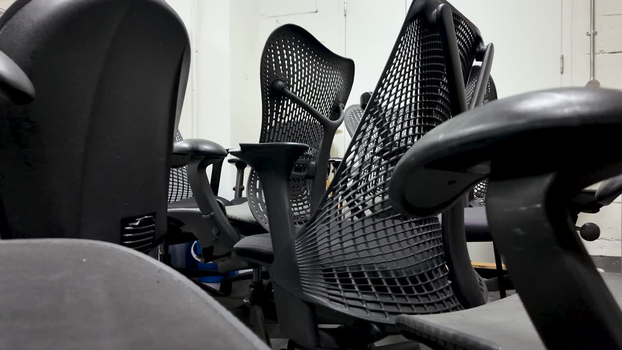Several discarded office chairs are piled up in a basement, creating a sense of abandonment and waste