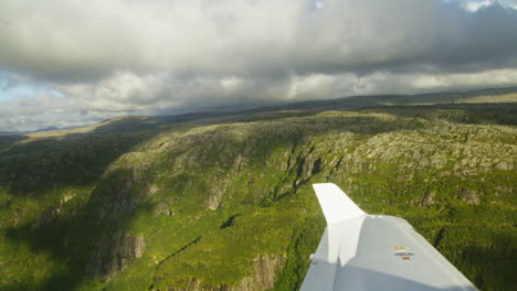 hand-held shot from inside an aeroplane looking out onto a mountain range