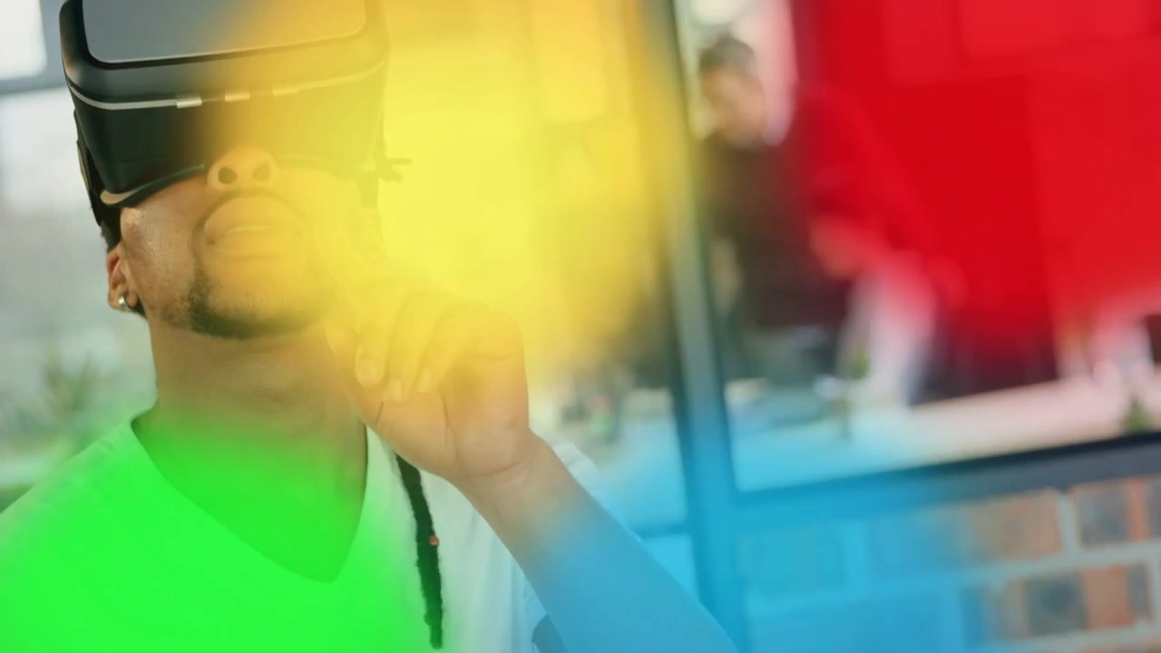 Hombre con casco de realidad virtual, levantando el dedo para activar superposiciones que muestran al equipo detrás de un cristal en una demostración tecnológica.