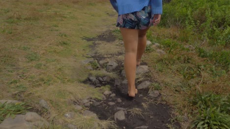 barefoot woman walking at rocky track on a windy day - big nobby peninsula in crescent head, nsw, australia