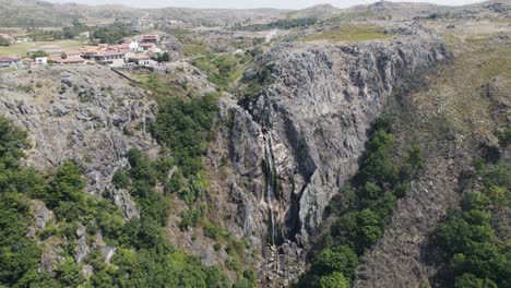 pueblo pintoresco en la cima del acantilado con una pequeña cascada en la ladera rocosa