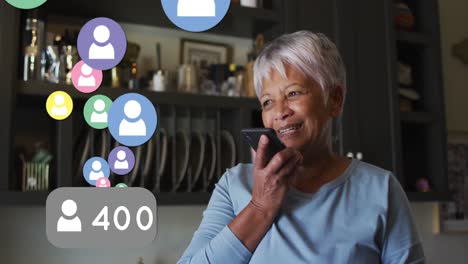 múltiples iconos de perfil flotando contra una mujer mayor afroamericana hablando en un teléfono inteligente en casa