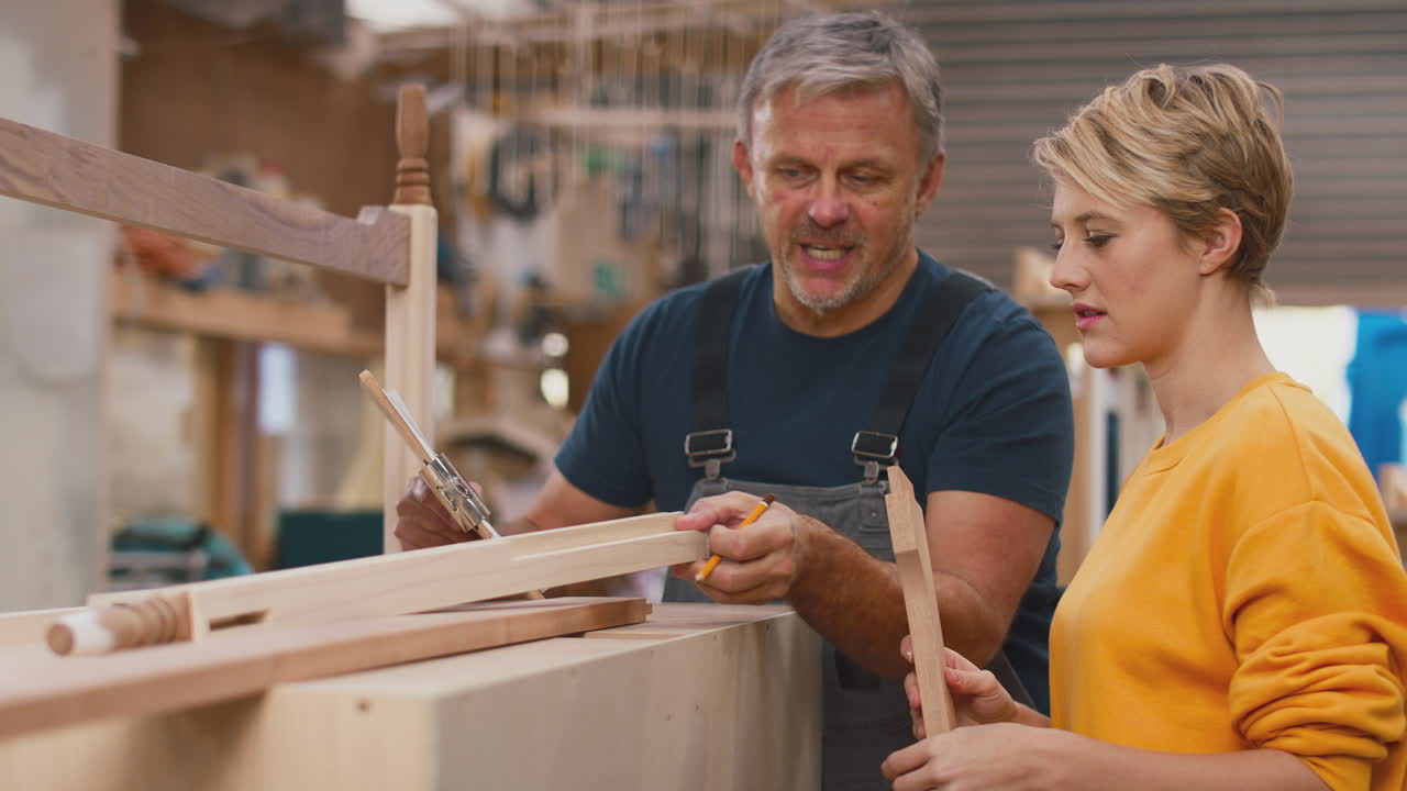 aprendiz femenina aprendiendo habilidades de un carpintero adulto en un taller de muebles