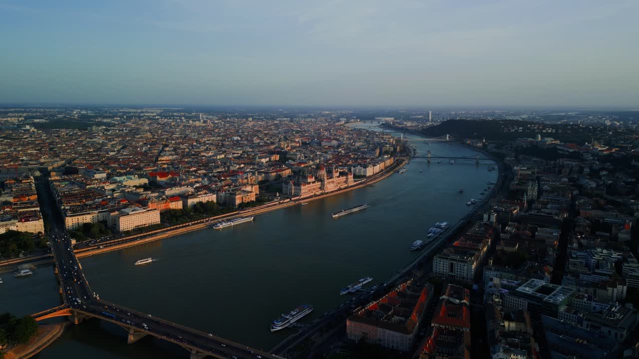 Aerial establishing of Budapest city curving along the Danube as Parliament building glows at twilight