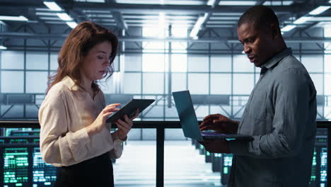 portrait of happy system administrators in data center using devices