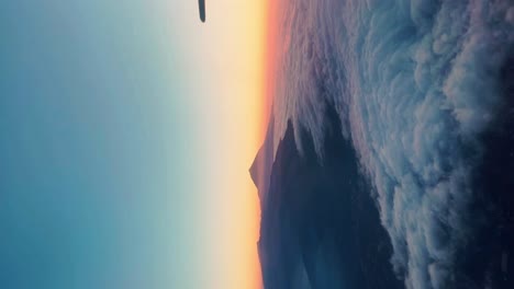 Aerial-view-from-an-airplane-of-mount-Teide-surrounded-by-clouds-at-sunset