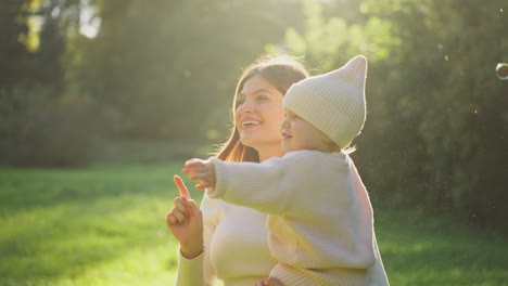 mother and daughter playing with bubbles in a park